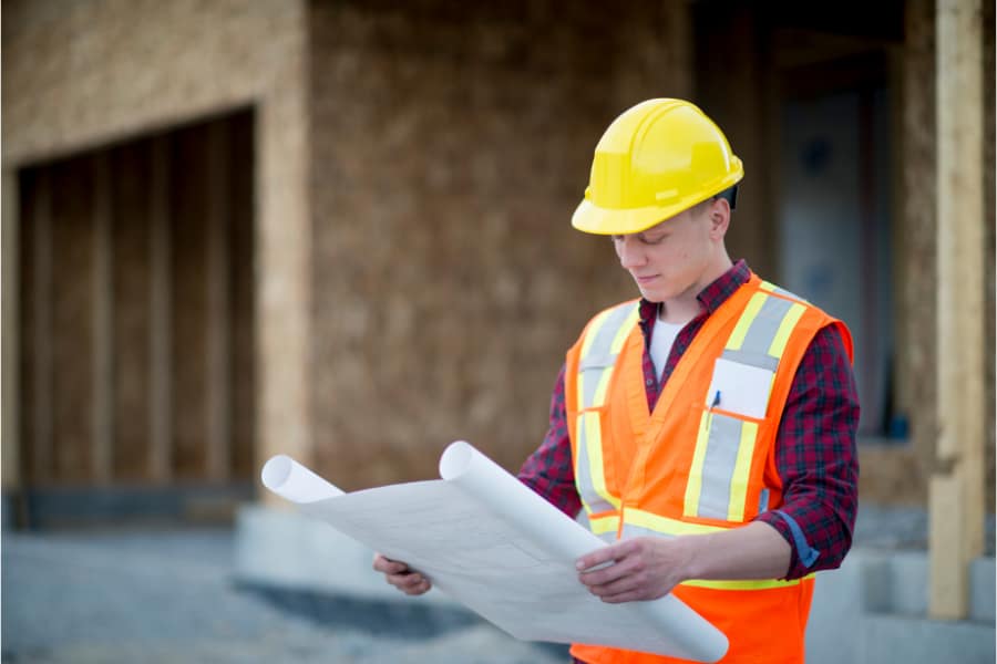 a man on a building site holding a permit plan
