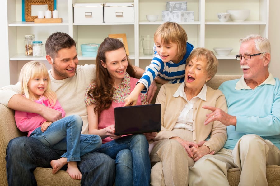 a family with parents, kids, and grandparents laughing on the couch