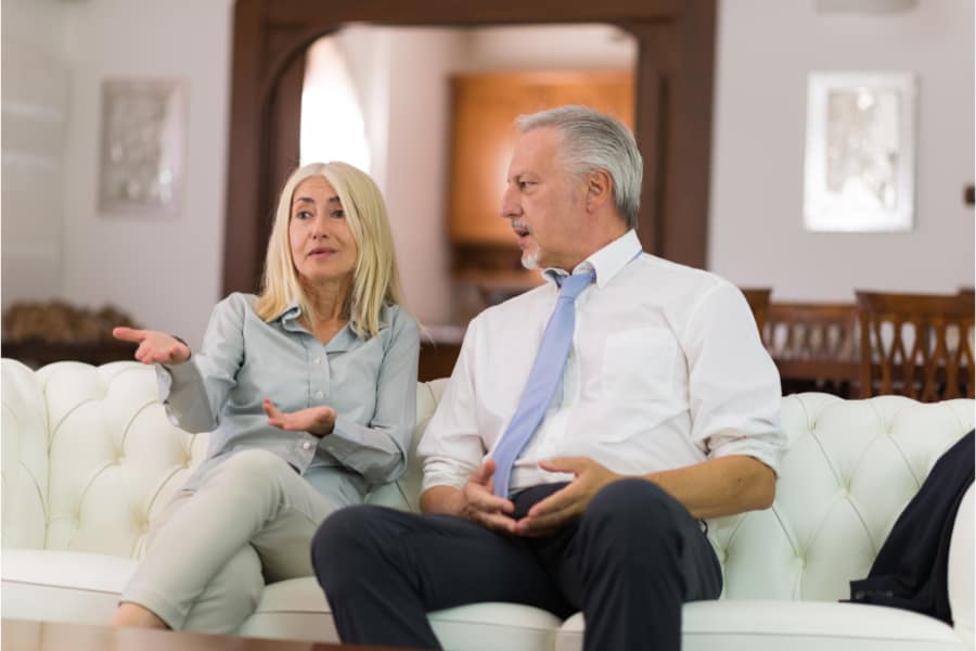 a man and woman sitting on a coach discussing