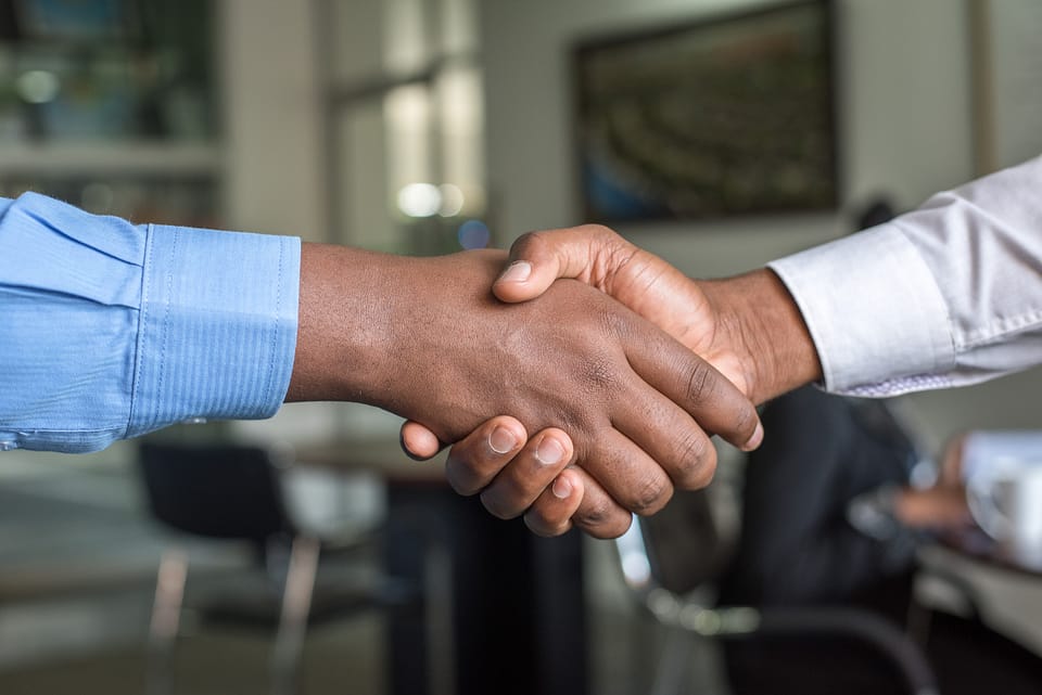 two men wearing shirts shaking hands