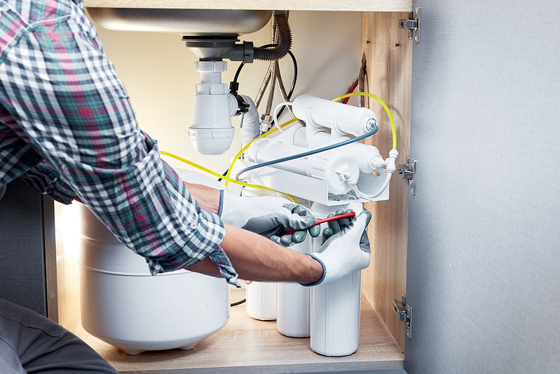 Technician installing or repairing system of water filtration.