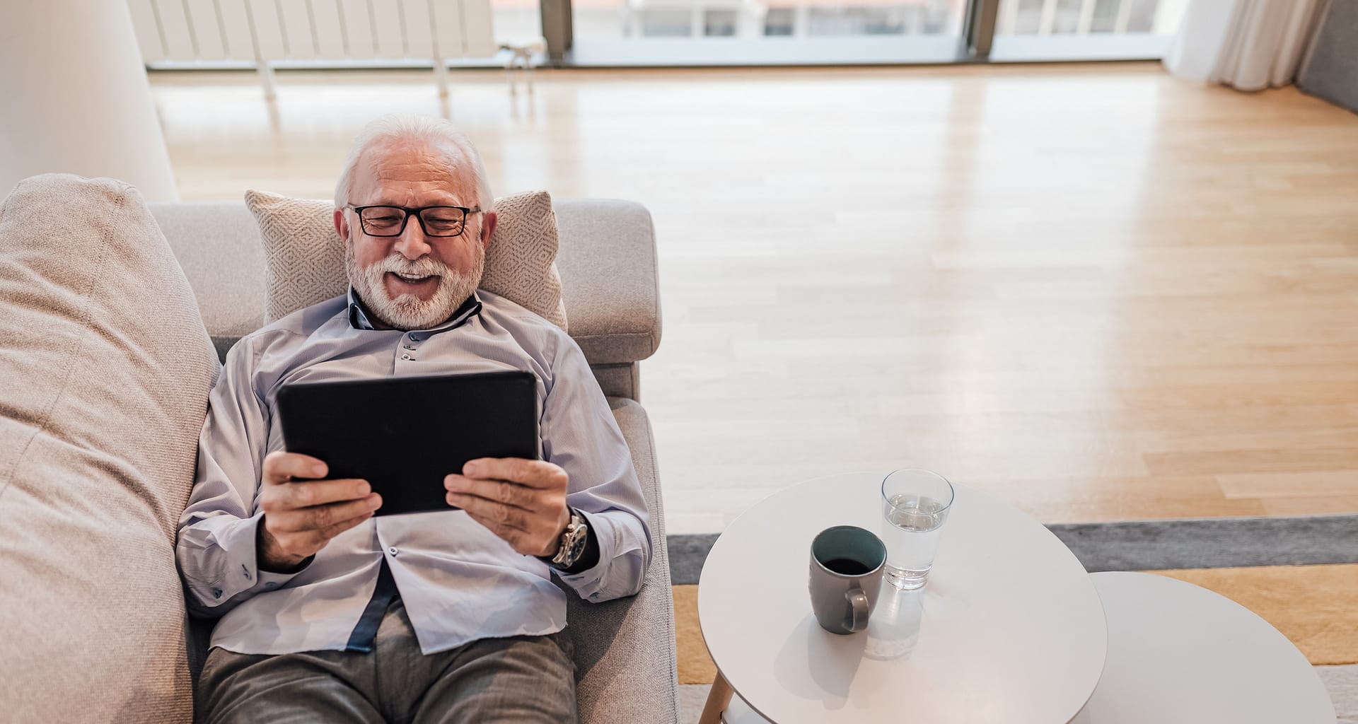 older man lying down on couch holding tablet gettyimages
