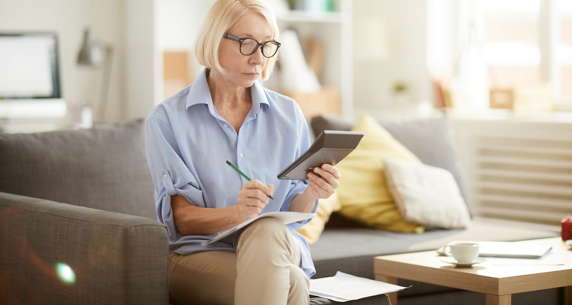 older woman sitting on a couch looking at a calculator