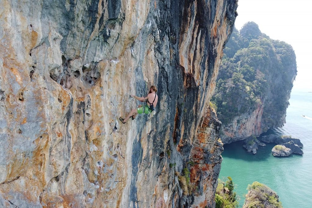 un escalador en railay tailandia, un acantilado plano con vistas al mar y a la isla desde su punto más alto