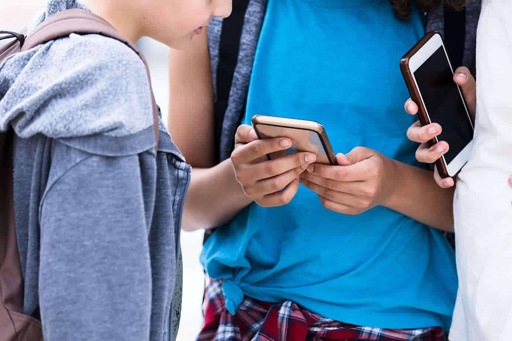 Three preteens looking at a smartphone is tiktok safe for kids