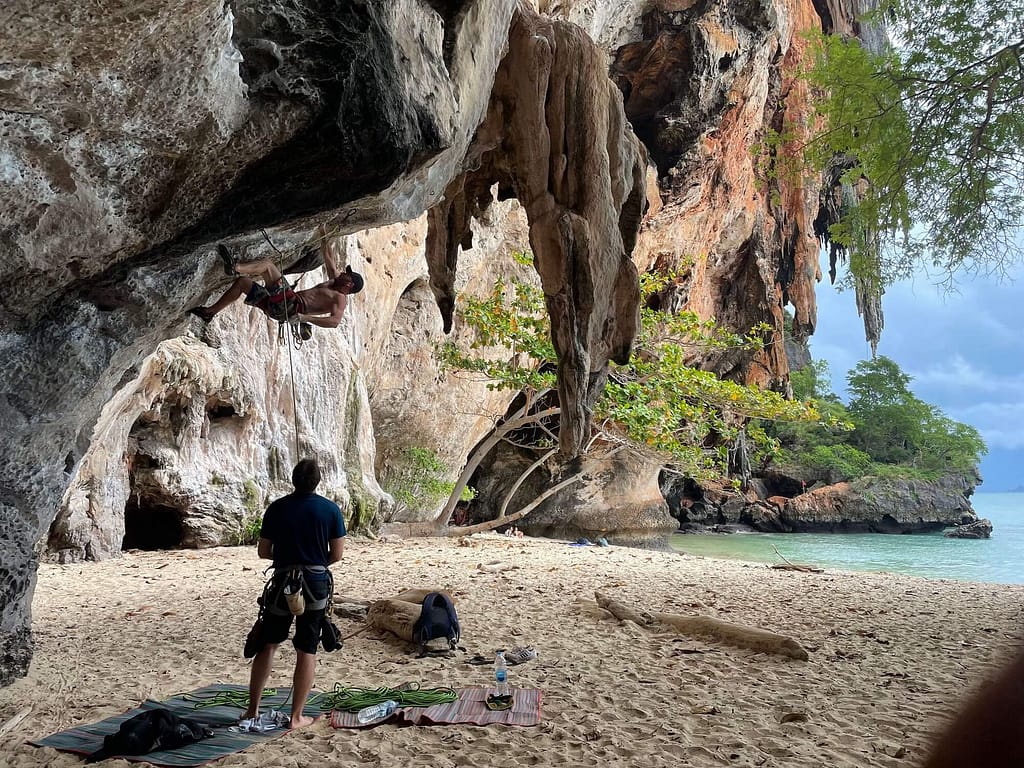 Un escalador en la playa de Railay Pranang prepara sus cuerdas bajo un saliente