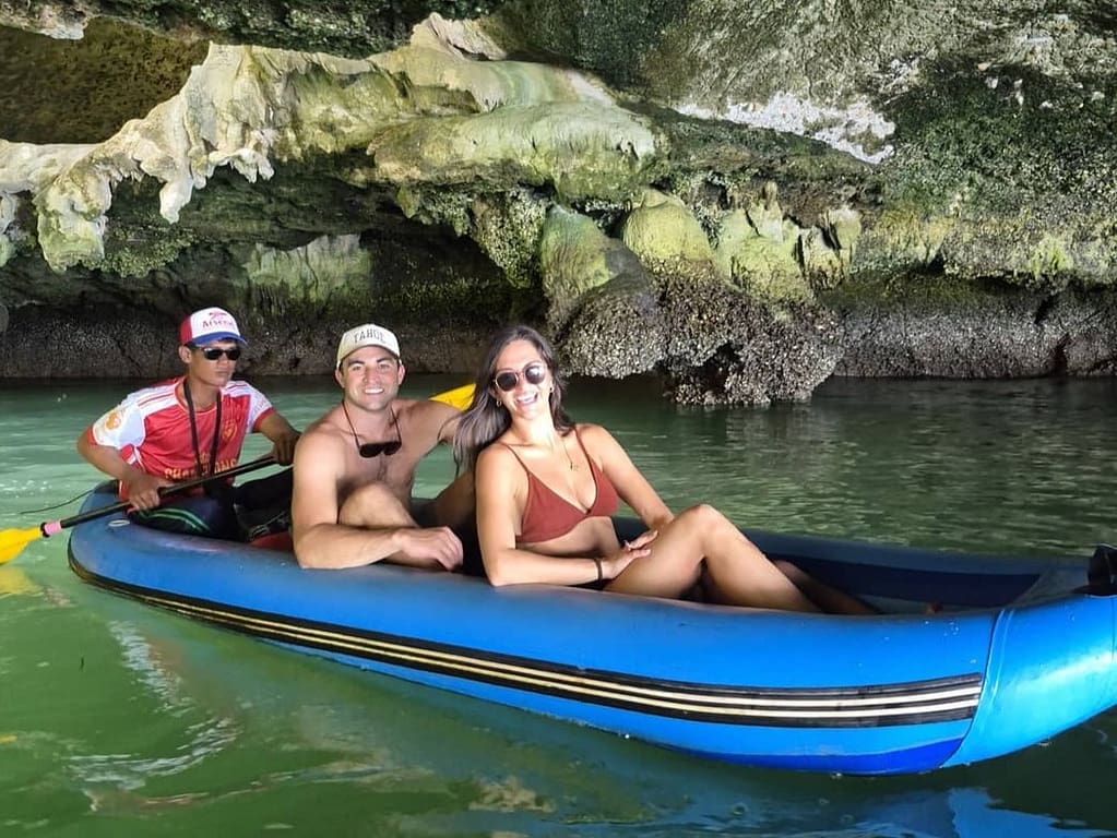 two people with their guide in a kayak in a cave