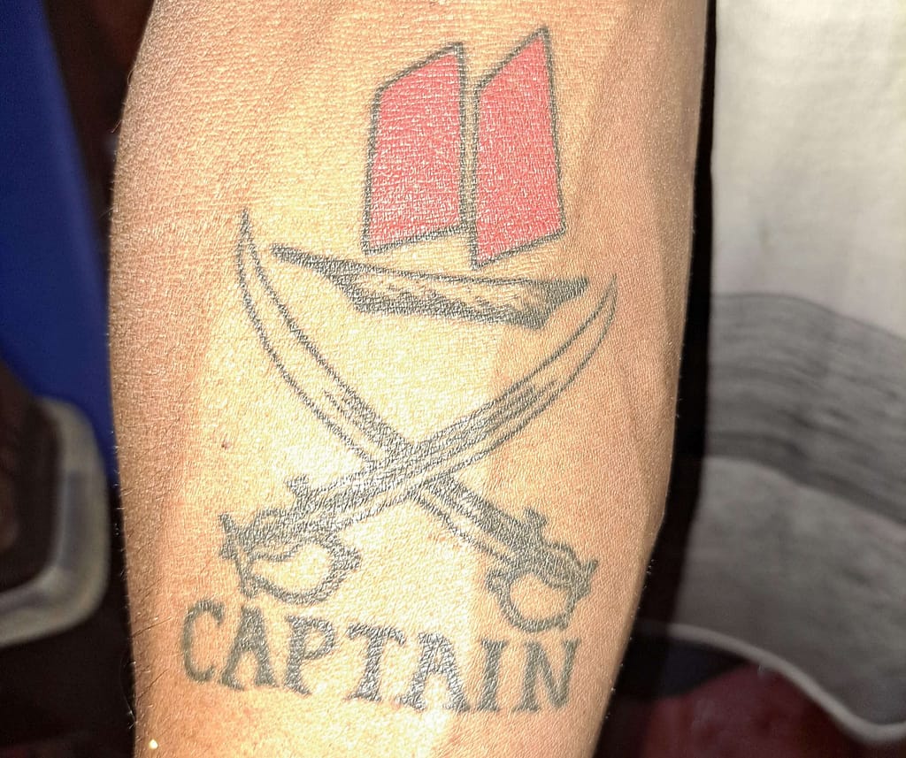 close up of a krabi sunset tour tattoo with crossed swords and the word captain underneath