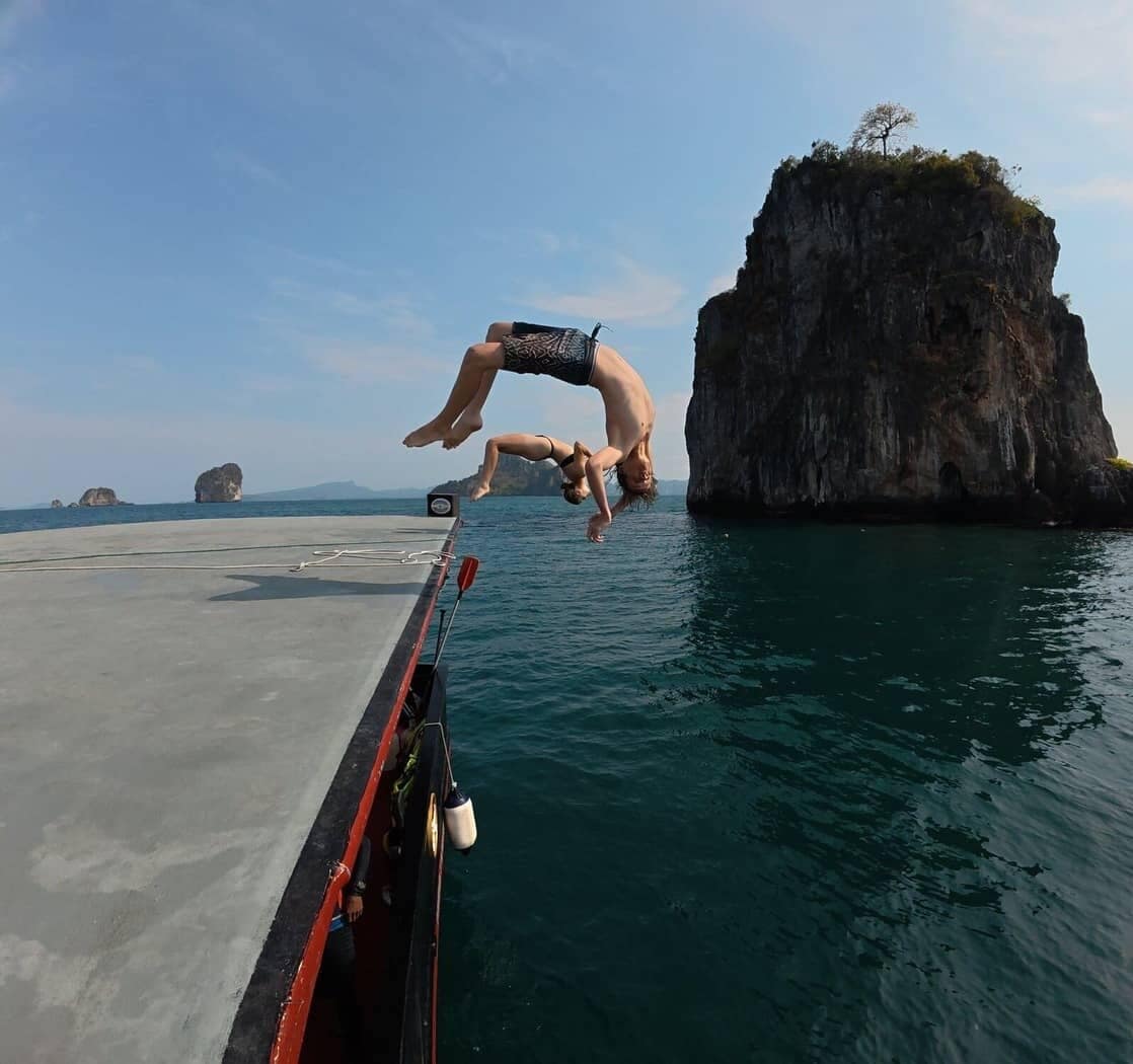 Turistas saltando y dando volteretas desde la cubierta superior del junco siamés en Krabi