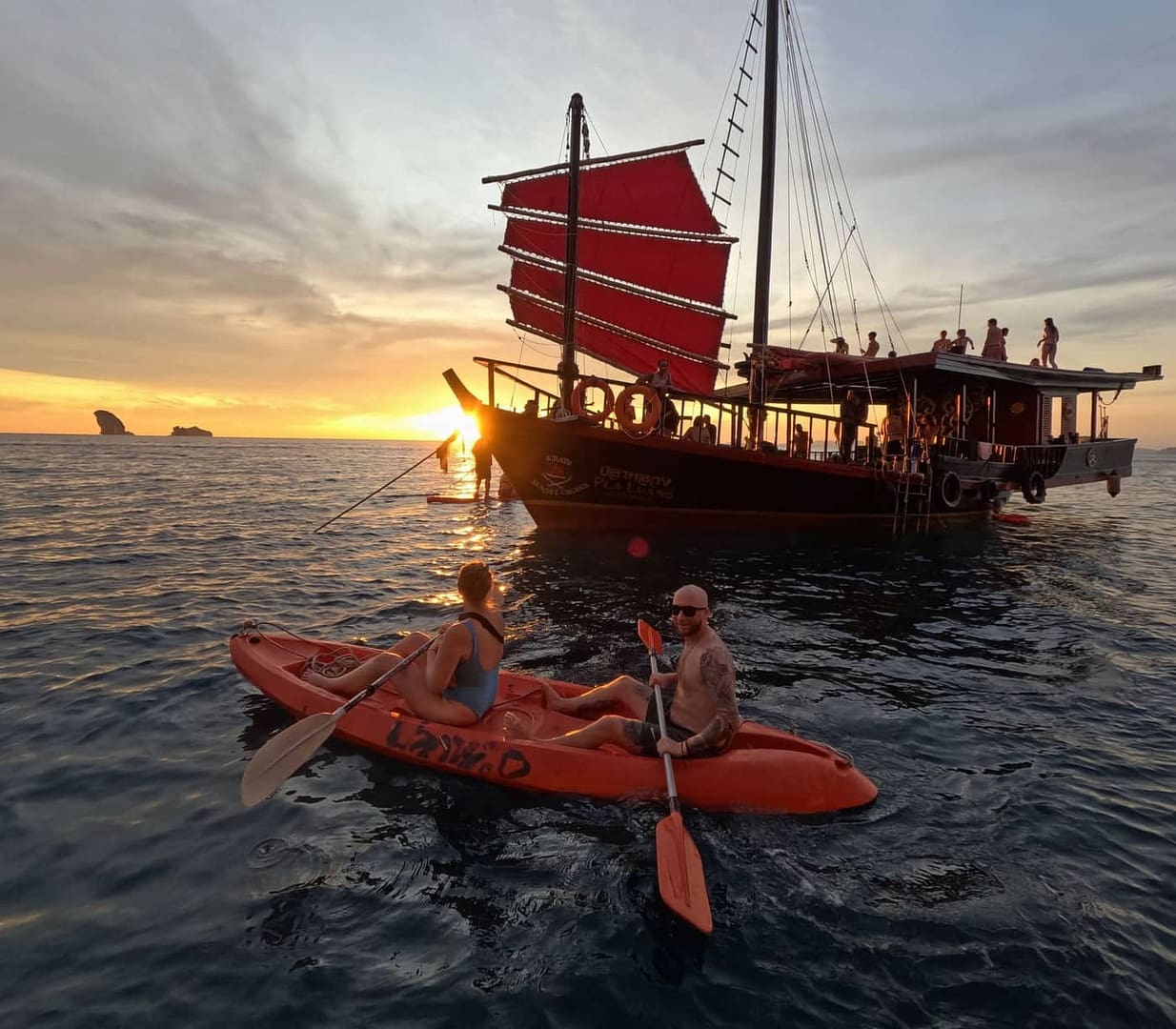Turistas practicando kayak junto a un junco al atardecer en Krabi