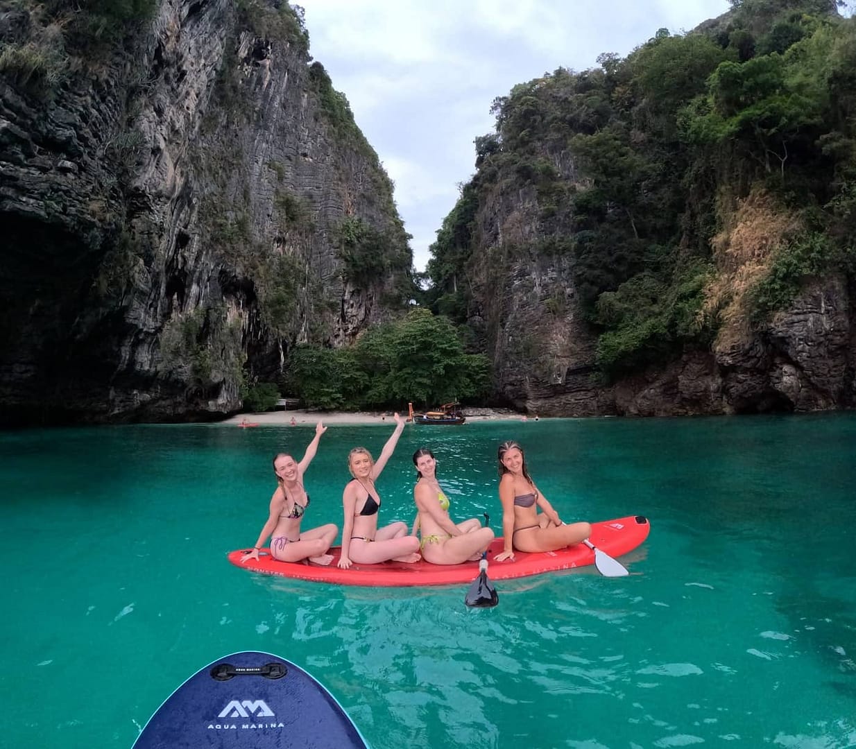 Huéspedes practicando paddle surf en aguas turquesas junto a una playa recóndita de una isla de Krabi