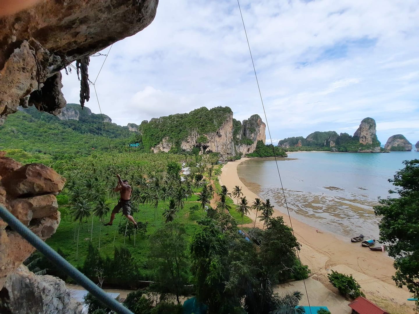 views over tonsai beach fro the cliffs with a rock climber hanging in open space