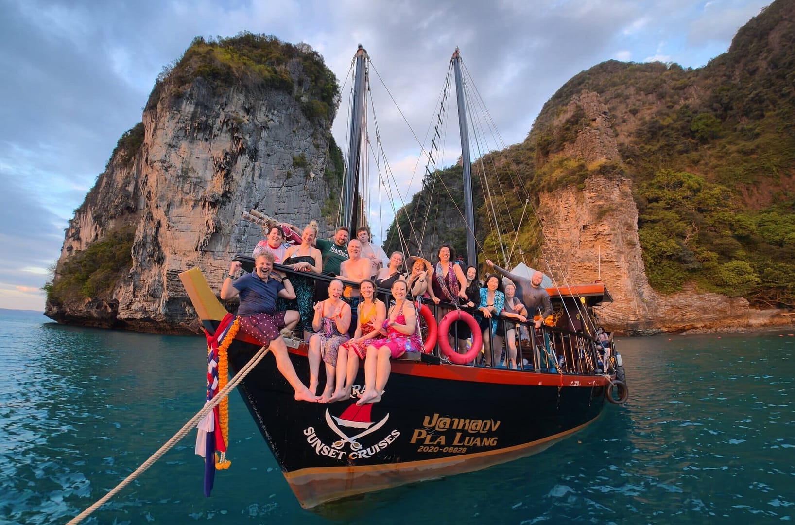 Group of people posing at the front of a junk boat with Poda Island in the background