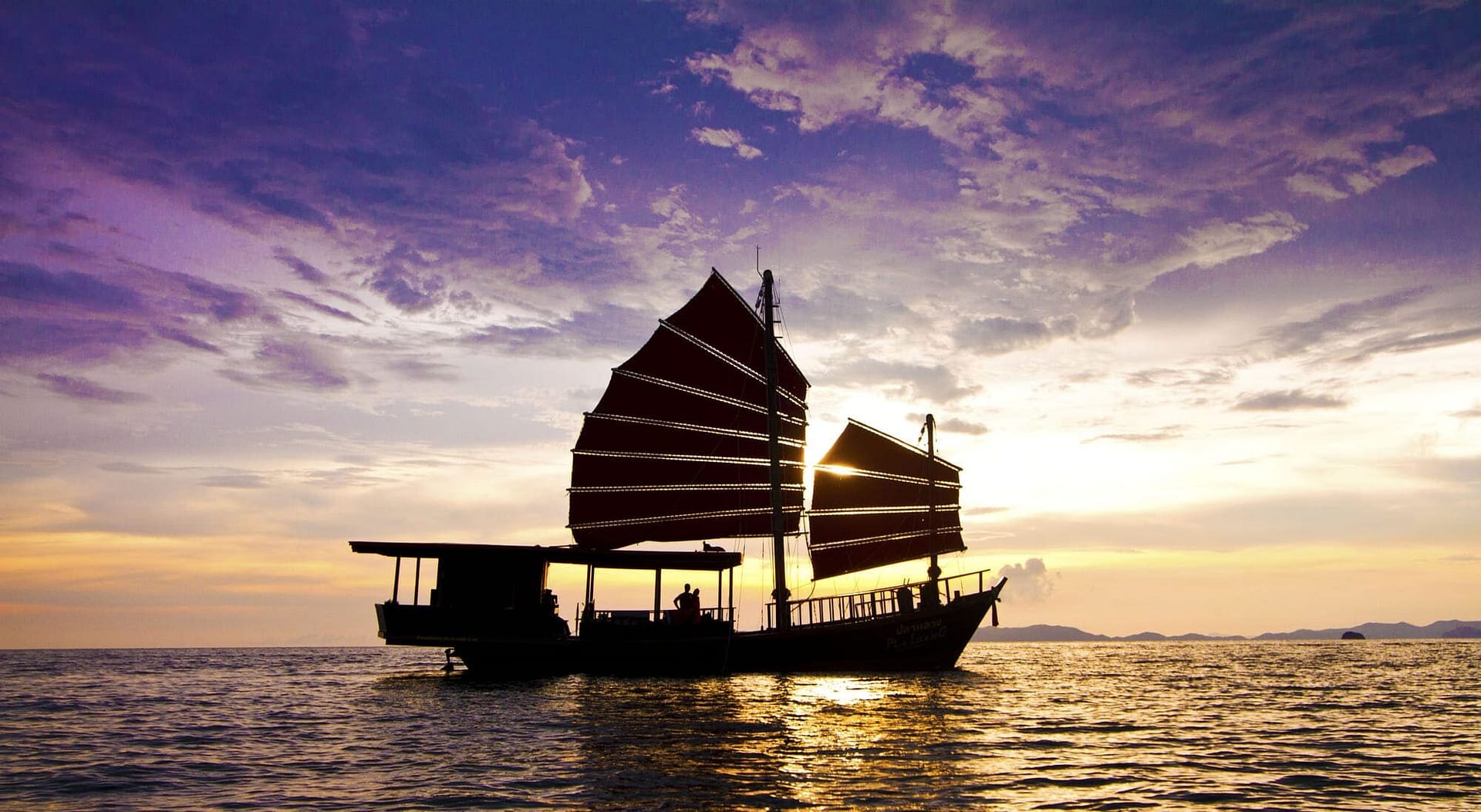 Junk boat sailing at sunset in the Andaman sea