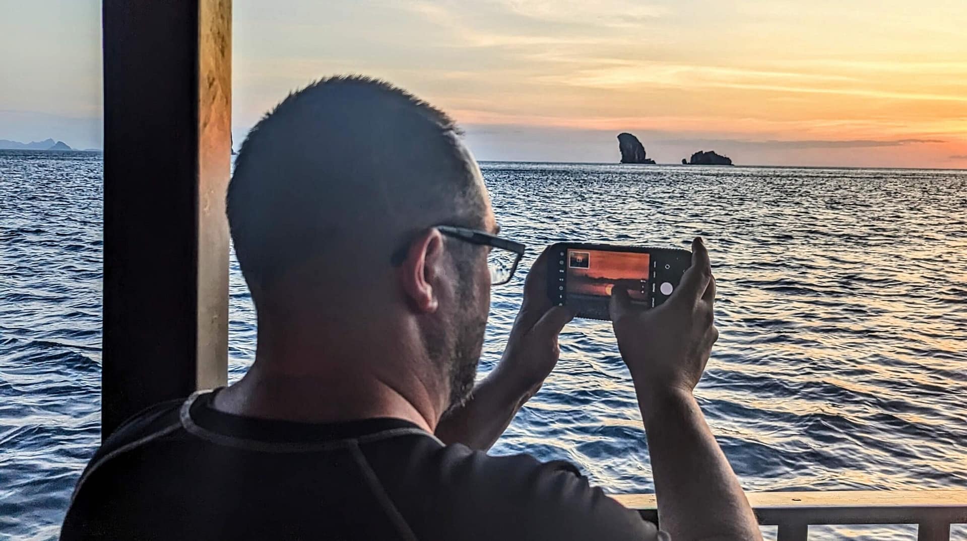 man taking a photo of a sunset with his phone