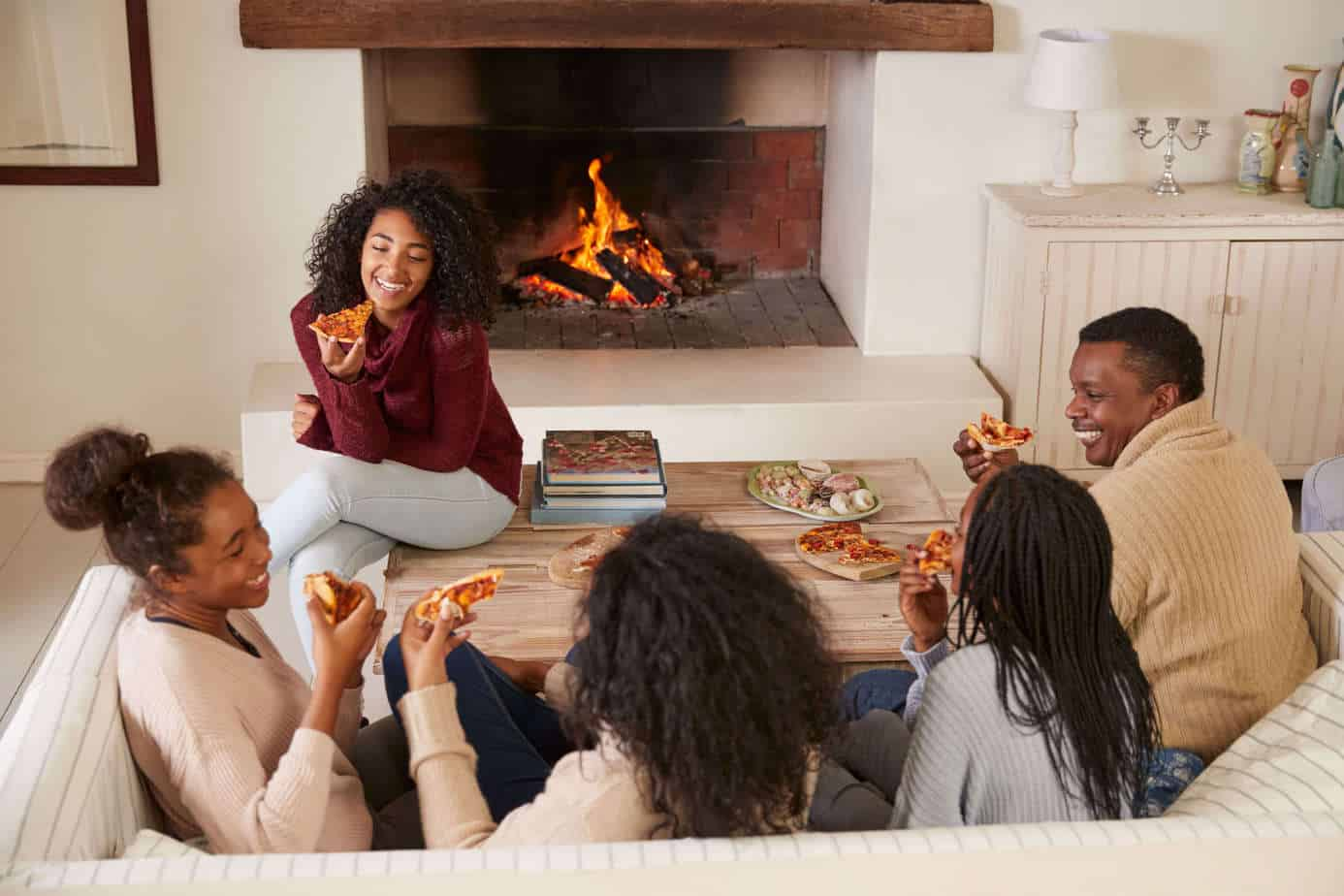 post-pandemic tech plan - mom, dad, three teenage girls eating pizza in the living room around a fire