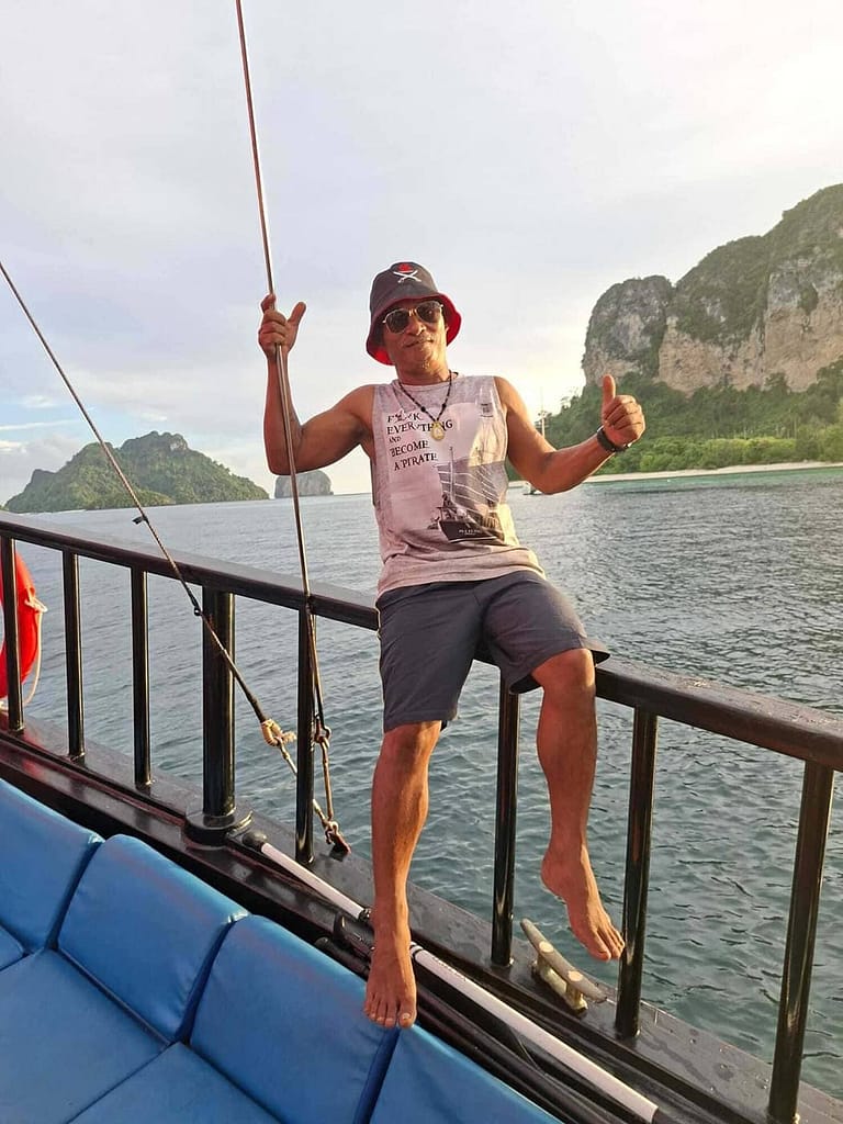 Pi Mee, capitaine de Krabi Sunset Cruises, debout à bord du bateau traditionnel en bois