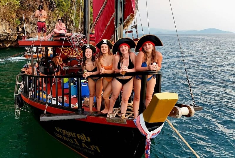 Group of girls standing at the front of of a traditional siamese junk boat at Poda Island in Krabi.