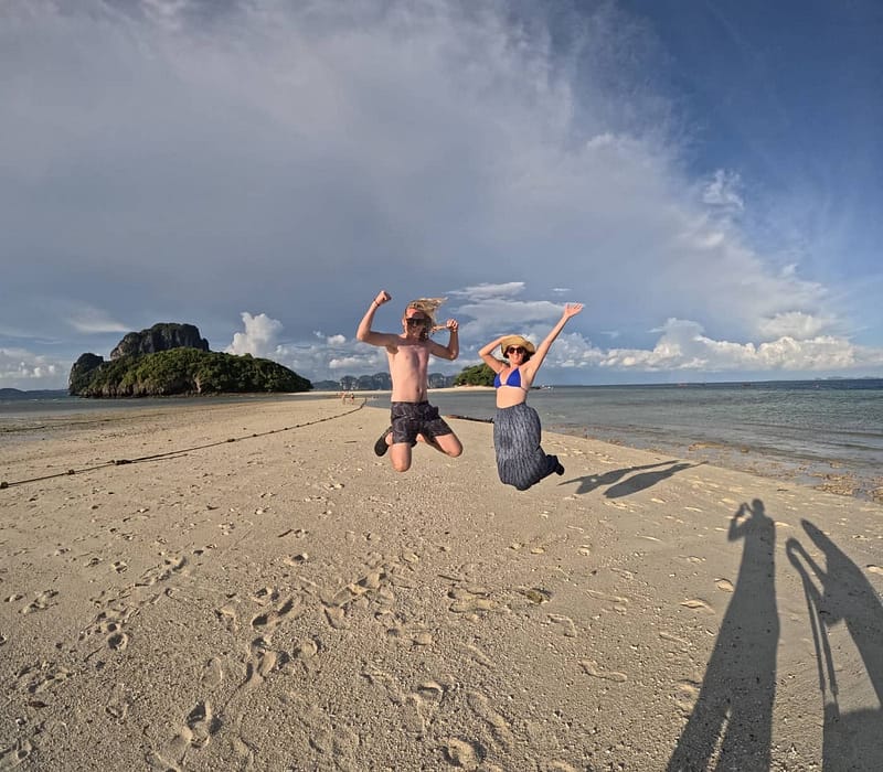 A couple jumping on the sandbar that links Chicken island and Tub island in Krabi.