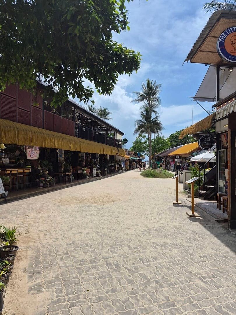 La calle Railay Walking Street en Krabi, Tailandia, está llena de restaurantes, tiendas y palmeras tropicales.