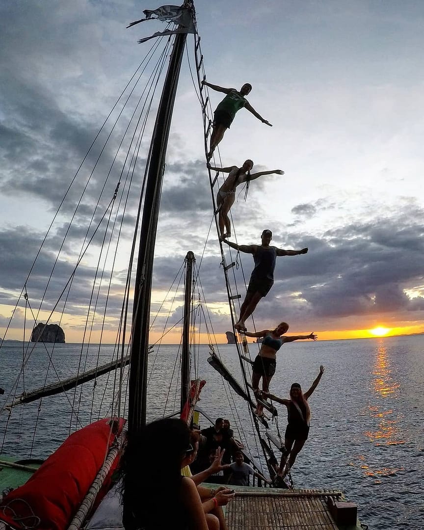Turistas trepando por el aparejo del junco siamés al atardecer en Krabi