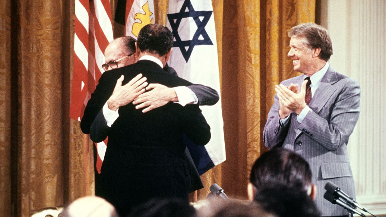 Carter claps as Sadat hugs Begin on September 17, 1978, after signing the peace agreement in the East Room of the White House. 