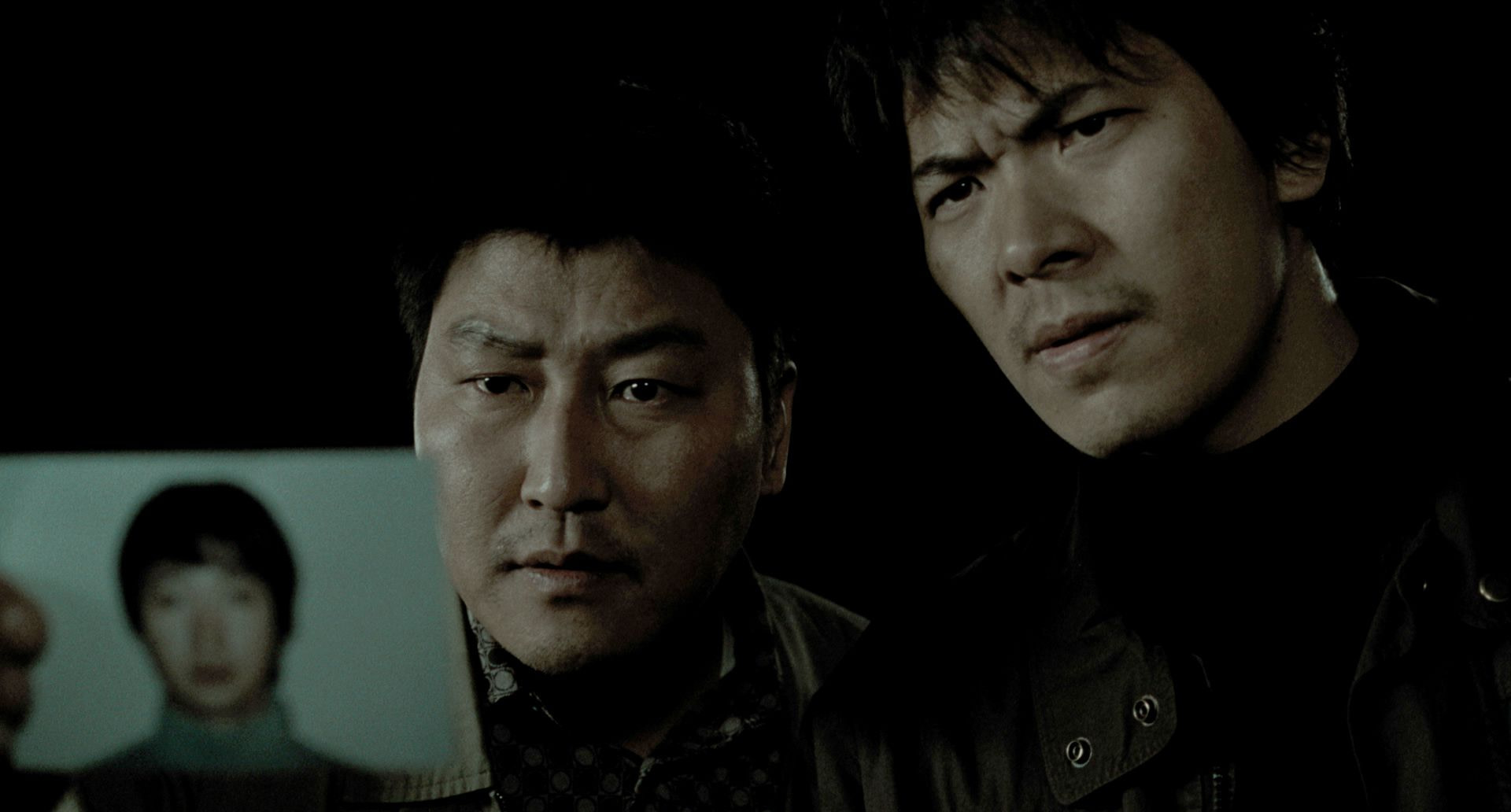 Detective Park (Song Kang-ho) and Seo (Kim Sang-kyung) holds the photo of murder suspect Park Hyeon-gyu (Park Hae-il ) in Memories of Murder