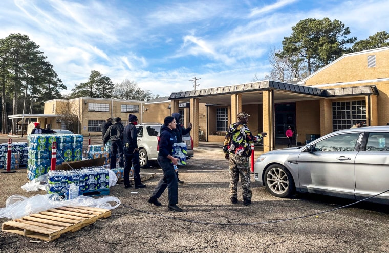 Image: A line of cars snakes past several city blocks as workers with the Mississippi Rapid Response coalition hand out bottled water to Jackson, Miss., residents on Dec. 27, 2022.
