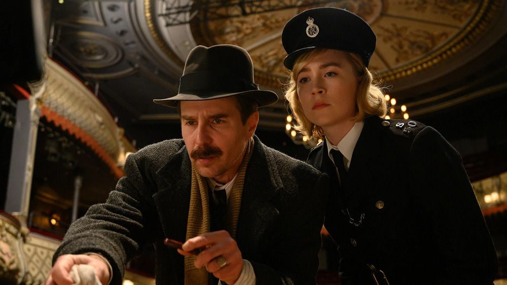 A detective with a thick moustache (Sam Rockwell) and a young woman in a constable outfit (Saoirse Ronan) in See How They Run.