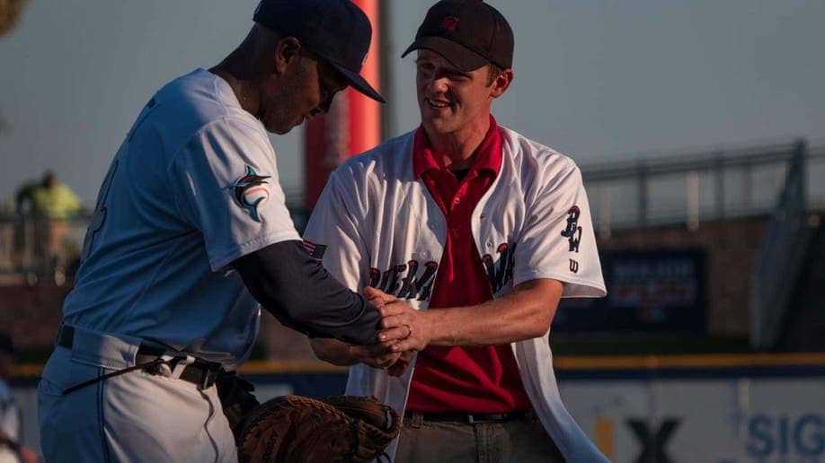 Baseball player shakes hand with man at game