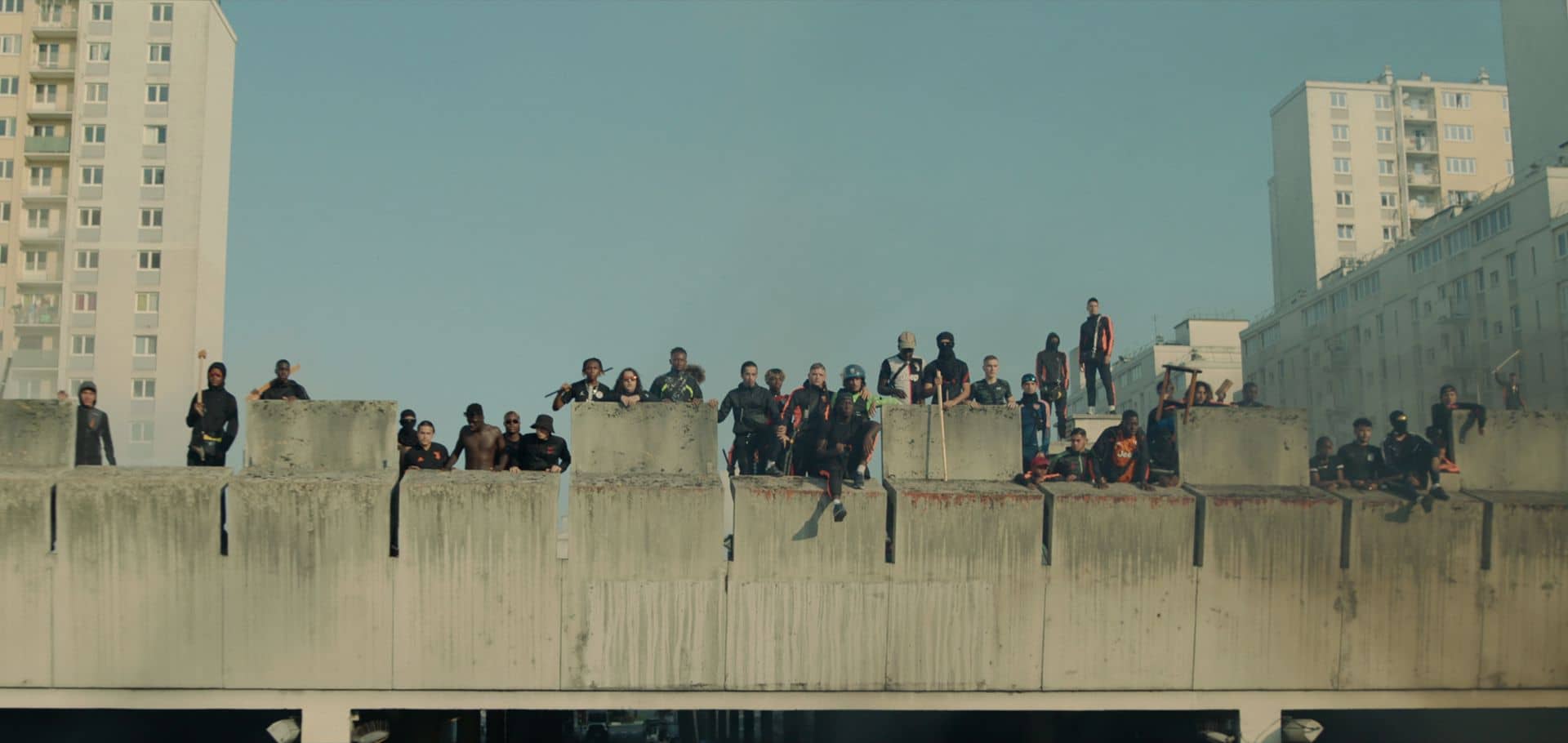 A large group of protestors stand atop a building looking down in Athena