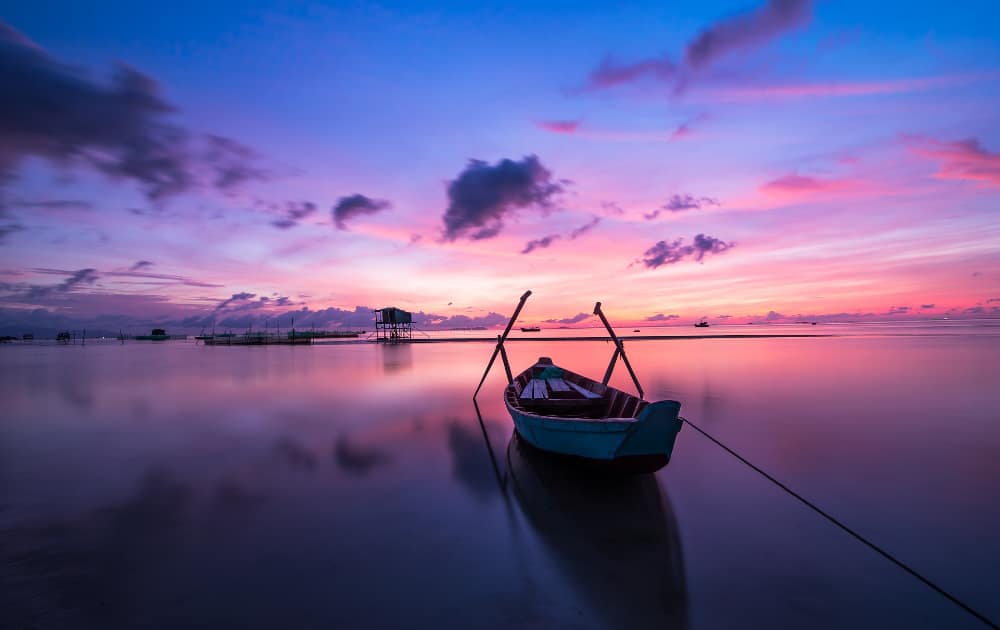 Coucher de soleil violet et rose en Thaïlande avec un petit bateau au premier plan
